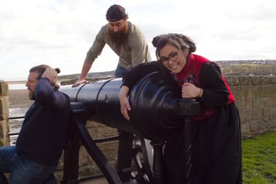 Three band members climbing a canon!