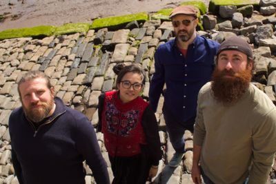 The four band members looking up from a cobbled street